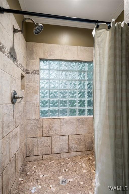 bathroom with crown molding and a tile shower