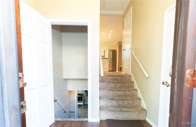 staircase featuring wood-type flooring and crown molding