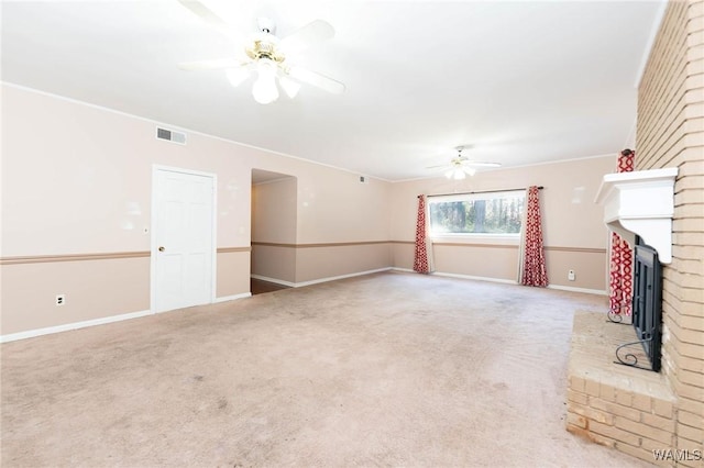 unfurnished living room with carpet flooring, ceiling fan, ornamental molding, and a fireplace