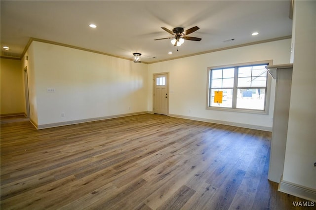 unfurnished living room with baseboards, visible vents, a ceiling fan, ornamental molding, and wood finished floors