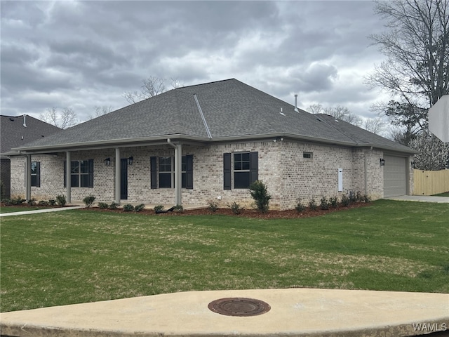 view of front of house with an attached garage, brick siding, roof with shingles, and a front yard