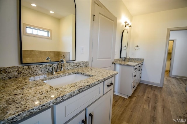 bathroom featuring two vanities, a sink, baseboards, and wood finished floors