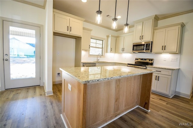 kitchen with stainless steel appliances, a sink, a center island, tasteful backsplash, and crown molding