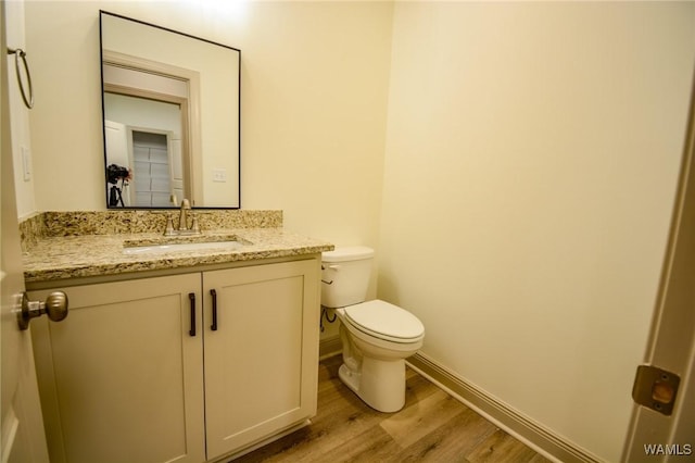 bathroom with vanity, wood finished floors, toilet, and baseboards