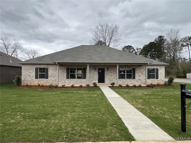 view of front of home featuring a front yard, roof with shingles, and brick siding