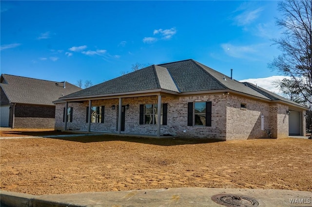 view of front of home with a garage, brick siding, and roof with shingles