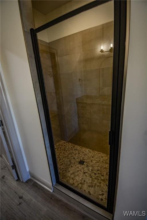 bathroom with a stall shower, wood finished floors, and baseboards