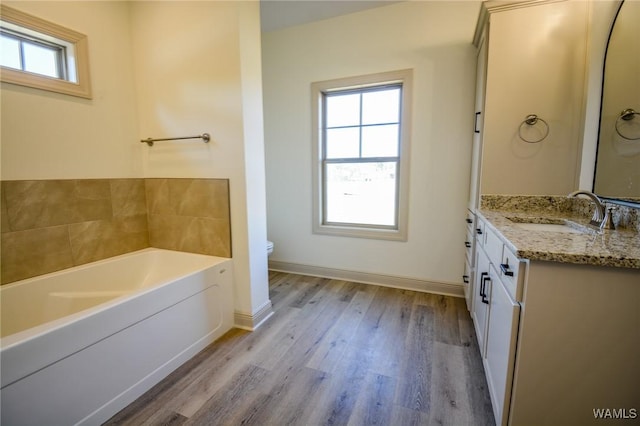 full bath with toilet, vanity, wood finished floors, baseboards, and a bath