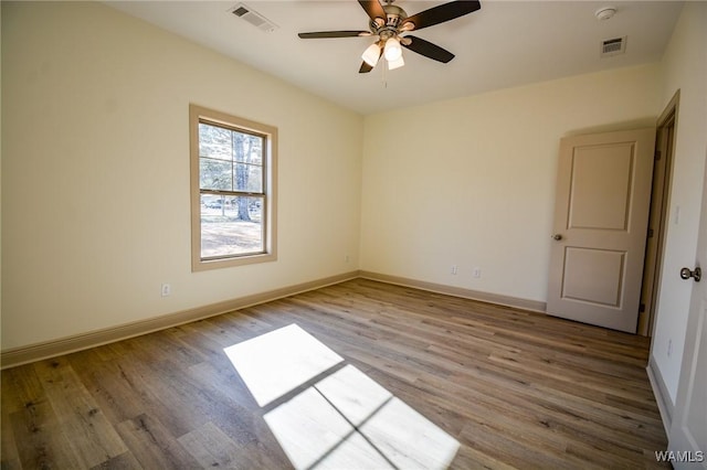 unfurnished room with baseboards, visible vents, and wood finished floors