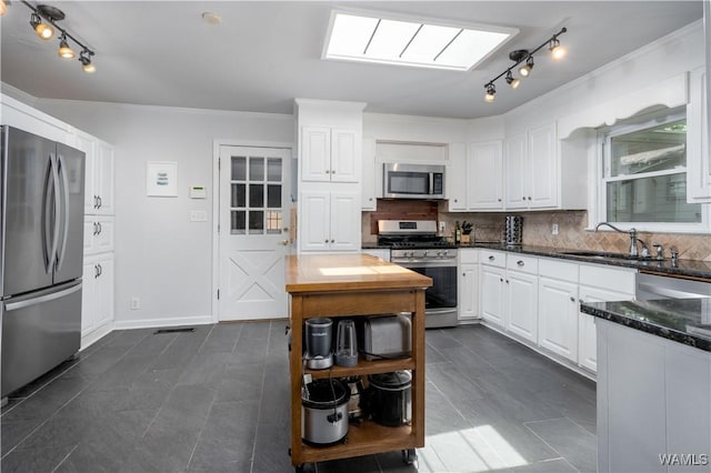 5324 Northwood Lake Dr W, Northport, AL 35473 - kitchen with appliances with stainless steel finishes, rail lighting, white cabinetry, decorative backsplash, and ornamental molding