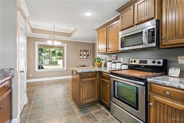 kitchen featuring pendant lighting, a raised ceiling, ornamental molding, kitchen peninsula, and stainless steel appliances