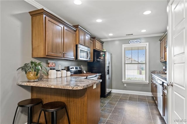 kitchen featuring stainless steel appliances, crown molding, a kitchen bar, and kitchen peninsula