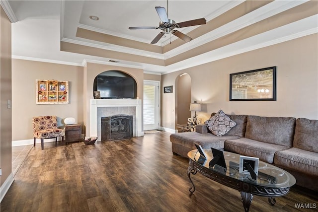 living room with dark hardwood / wood-style flooring, a tray ceiling, and ornamental molding