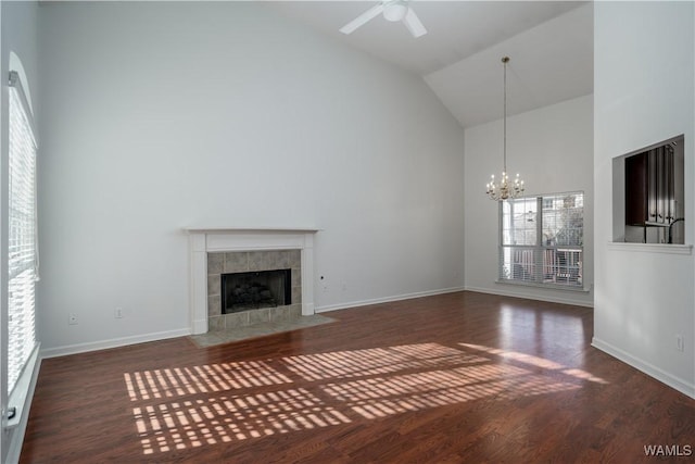 unfurnished living room with dark hardwood / wood-style flooring, a fireplace, high vaulted ceiling, and ceiling fan with notable chandelier