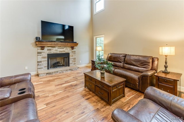 10998 Sleepy Valley Rd, Northport, AL 35475 - living area featuring light wood-style floors, a towering ceiling, baseboards, and a stone fireplace