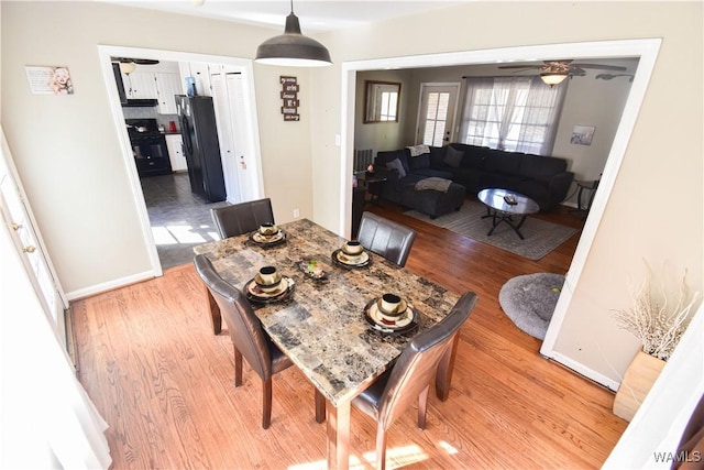 dining space featuring ceiling fan, light wood-style flooring, and baseboards