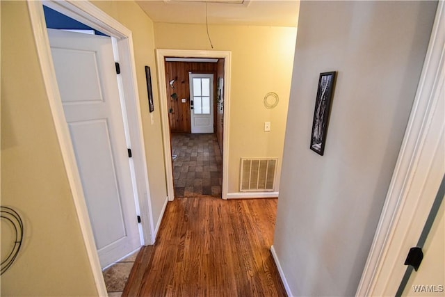 hall with attic access, visible vents, baseboards, and wood finished floors