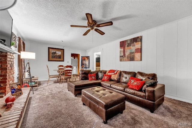 carpeted living room with ceiling fan, a textured ceiling, and a brick fireplace