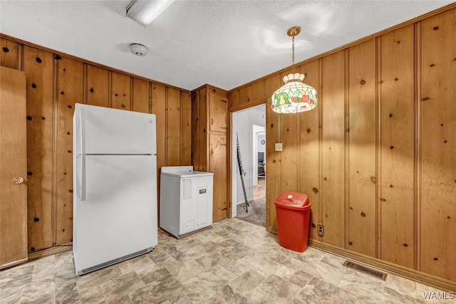 laundry room with wooden walls and a textured ceiling