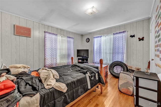 bedroom with light hardwood / wood-style flooring and wooden walls