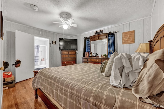 bedroom with wood walls, ceiling fan, light wood-type flooring, a textured ceiling, and ornamental molding