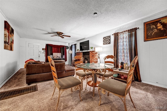 carpeted dining area featuring a textured ceiling, a brick fireplace, and ceiling fan