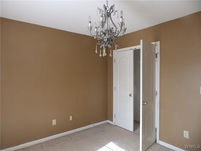 carpeted empty room featuring an inviting chandelier