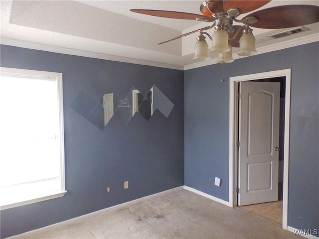 empty room featuring light colored carpet, a ceiling fan, baseboards, visible vents, and crown molding