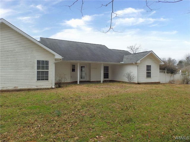 rear view of house with fence and a lawn