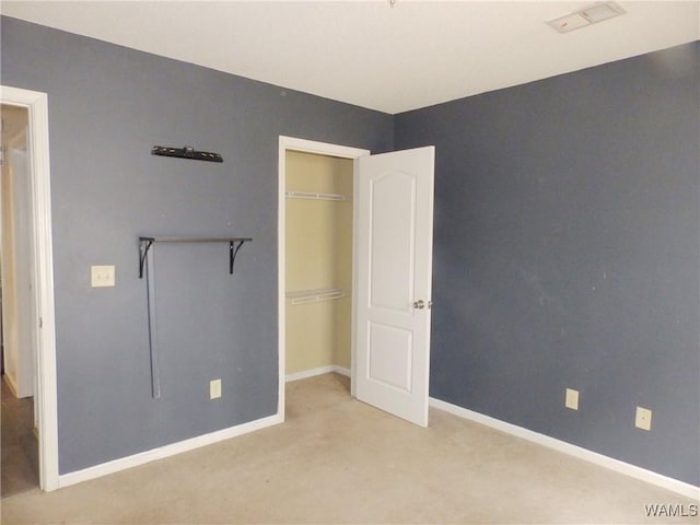 unfurnished bedroom featuring light carpet, a closet, visible vents, and baseboards