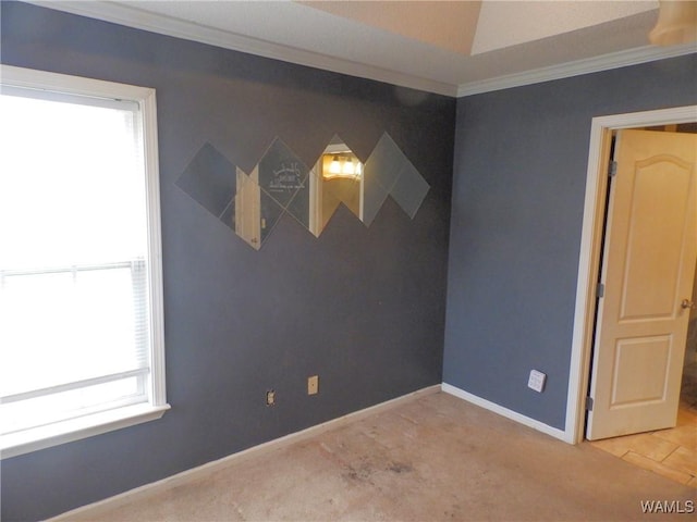 spare room with an accent wall, baseboards, and crown molding