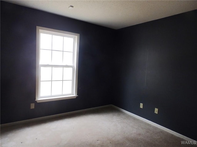 carpeted empty room featuring baseboards and a textured ceiling