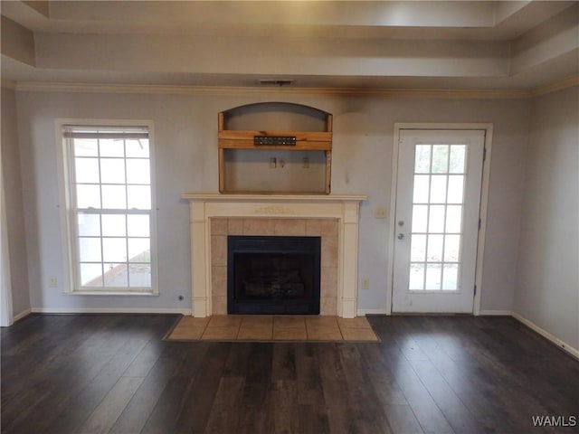 unfurnished living room featuring baseboards, a raised ceiling, dark wood-type flooring, and a tile fireplace