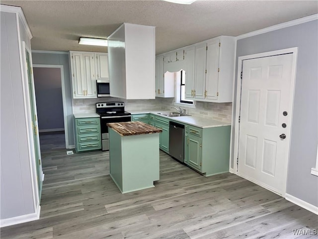 kitchen featuring decorative backsplash, appliances with stainless steel finishes, sink, green cabinetry, and a center island