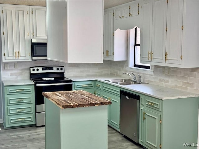 kitchen featuring a center island, white cabinets, green cabinetry, decorative backsplash, and stainless steel appliances