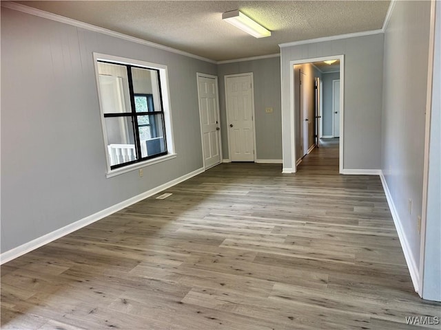 spare room with light hardwood / wood-style flooring, a textured ceiling, and ornamental molding