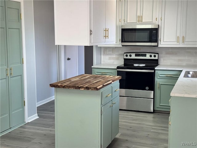 kitchen featuring green cabinets, light hardwood / wood-style flooring, decorative backsplash, white cabinetry, and stainless steel appliances