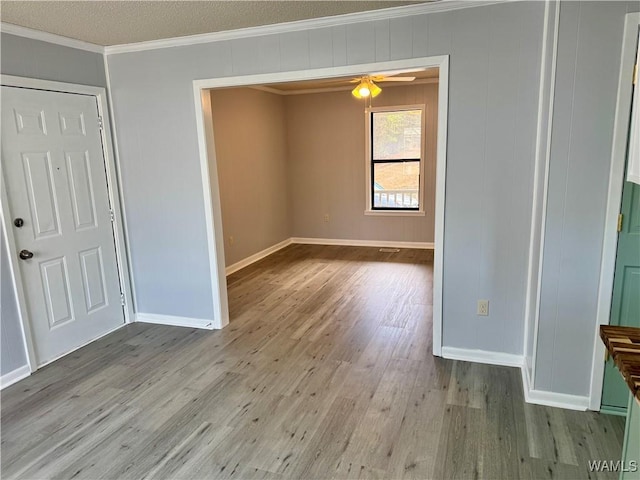 interior space featuring ceiling fan, crown molding, light hardwood / wood-style floors, and a textured ceiling