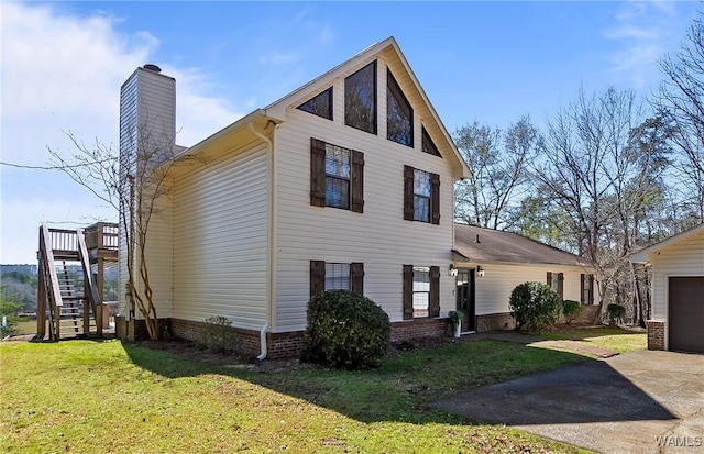 view of front of house featuring a front yard, a chimney, stairs, an outdoor structure, and a garage