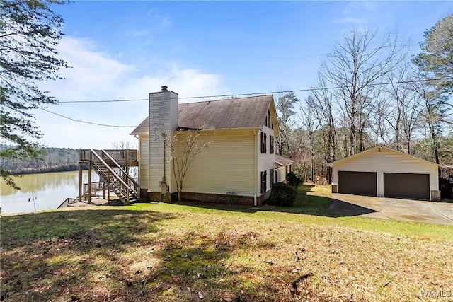 view of side of property with a yard, a chimney, a detached garage, and an outdoor structure