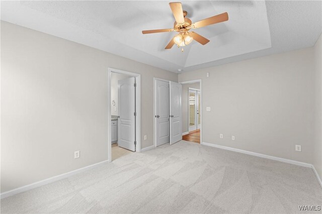 unfurnished bedroom featuring ensuite bathroom, baseboards, a ceiling fan, and carpet flooring