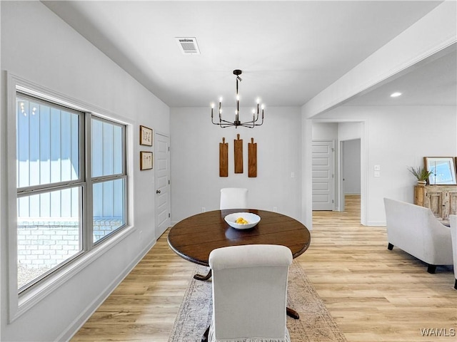 dining room featuring light wood-type flooring, an inviting chandelier, baseboards, and visible vents