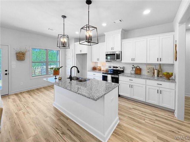 kitchen with stainless steel appliances, visible vents, white cabinetry, and a sink
