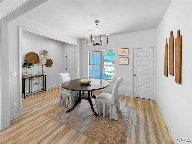 dining room featuring visible vents, baseboards, light wood finished floors, and a notable chandelier
