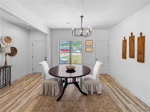 dining room with light wood-type flooring, an inviting chandelier, baseboards, and visible vents