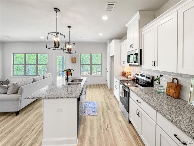 kitchen with visible vents, a sink, open floor plan, light wood finished floors, and stainless steel appliances