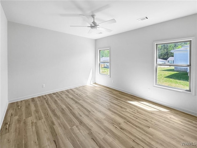 unfurnished room with a wealth of natural light, visible vents, and light wood-style flooring