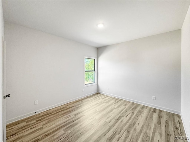 unfurnished room featuring baseboards and light wood finished floors