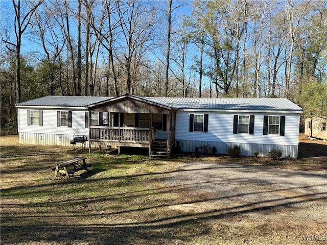 manufactured / mobile home featuring covered porch and a front lawn