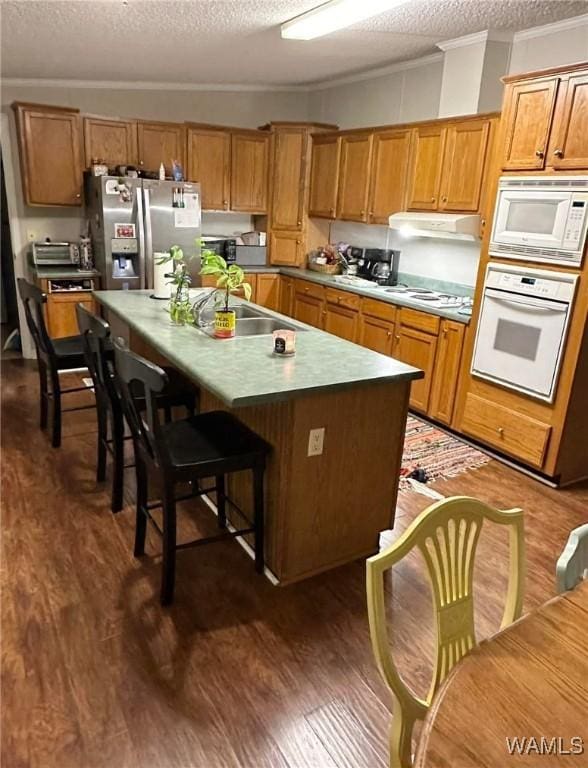 kitchen with dark hardwood / wood-style floors, a center island, a textured ceiling, and white appliances